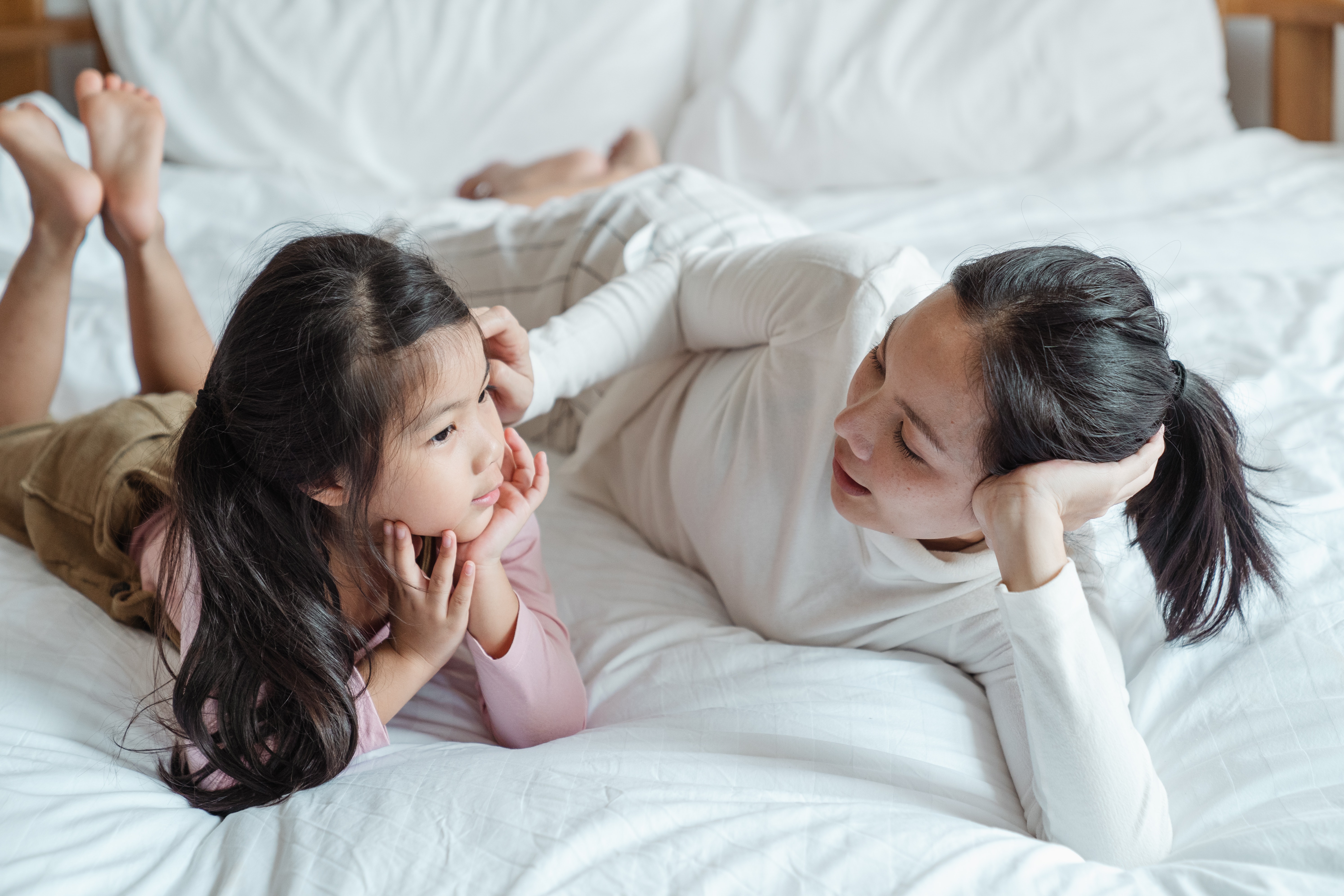 mother and daughter talking in bed